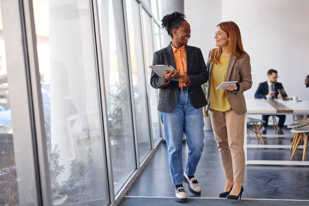 istock Two businesswomen walking and talking in modern office 2202814525