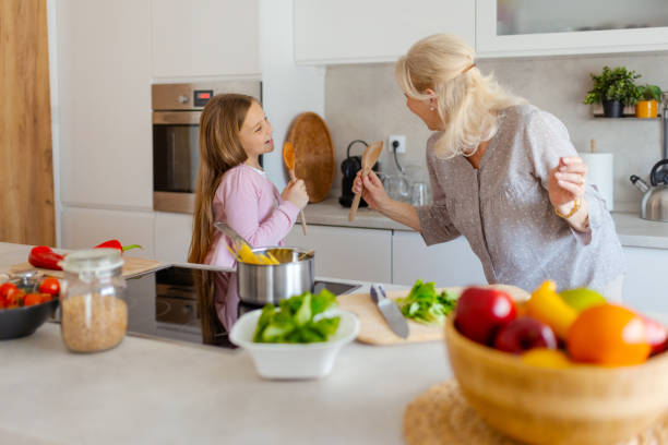 istock Kitchen Concert: Grandmother and Granddaughter Sing While Cooking 2202815100