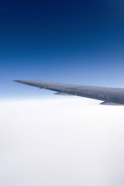 istock An airplane wing gracefully soars above the fluffy clouds in a beautiful clear blue sky. Blue and white sky background under the wing of an airplane. The concept of travel. 2202815142