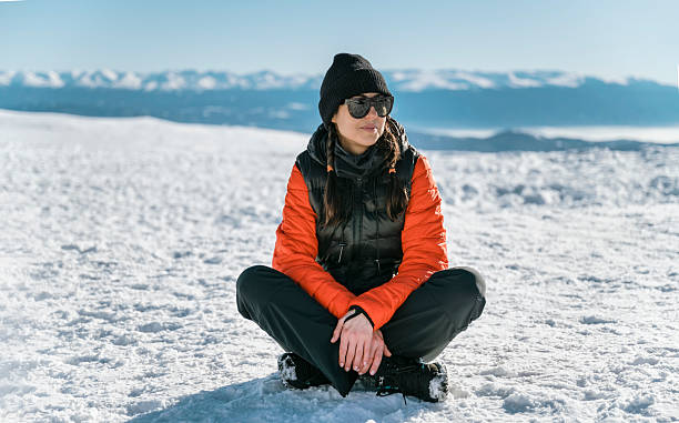 istock Young Woman Sitting  in the winter mountain 2202817621