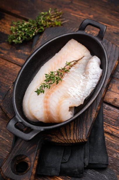 istock Pristine raw cod fillet, waiting to be marinated and cooked to perfection for a delightful dining experience. wooden background. top view 2202817719