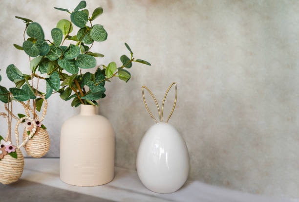 istock Easter decoration with green plant in vase and golden easter eggs and easter bunny 2202818957