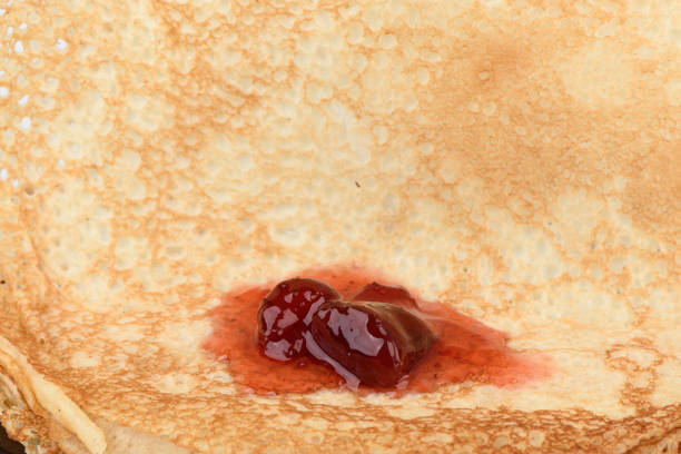 many thin pancakes with jam on a green background