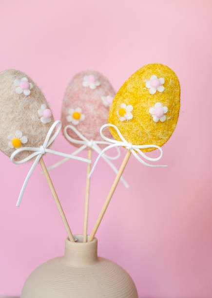 Pink ,yellow and beige fabric easter eggs with sticks on pink background