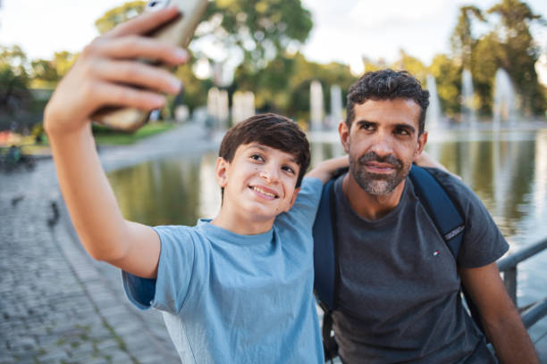 istock Father and son taking a selfie by the park fountain 2202823009
