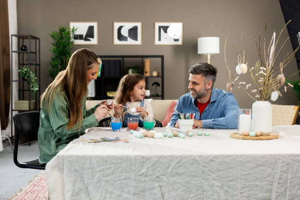 istock Young girl sharing a special moment with her parents, decorating Easter eggs 2202824793