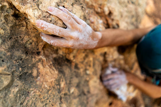 istock fearlessly climbs up the rock using white magnesia powder, holds her hand to the ledge in the relief, 2202826052