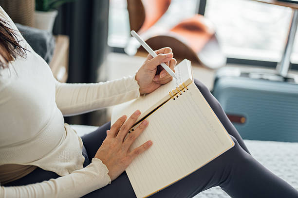 istock woman sitting on bed and writing journal 2202827606