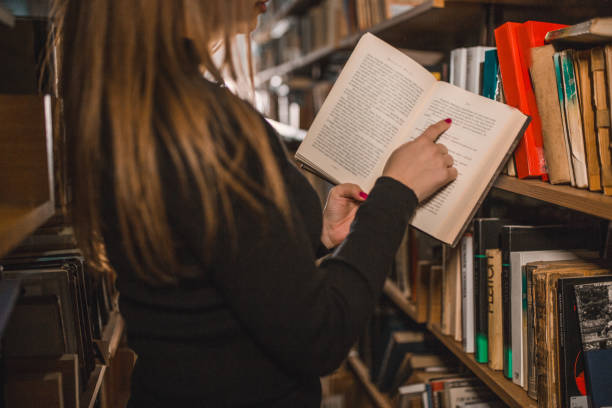 istock An unrecognizable female student is reading a book in the library and enjoying an exciting novel 2202828340