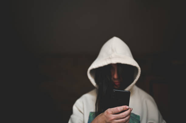 Person in hood with mobile phone close up.