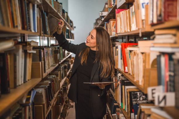 istock Female librarian searches books in the library using a digital tablet 2202829210