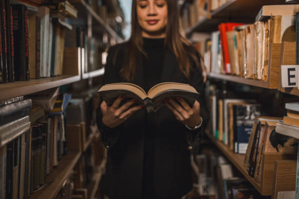 istock Female student is reading a book in the library 2202829311
