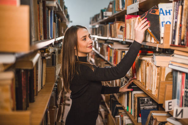 istock Female student takes a book from the shelf in the library 2202829363