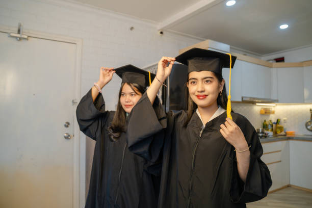istock two young woman wearing graduation gown 2202829367