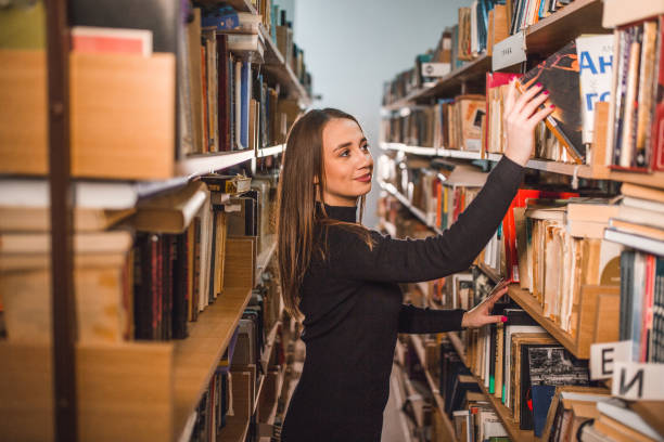 istock Gorgeous librarian takes a book from the shelf in the library 2202829444