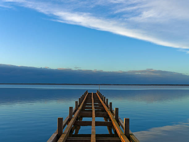 istock Wooden Jetty in sunlight and blue sky over lake 2202829516