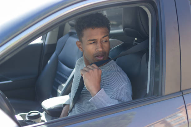 istock Young man fastening seat belt in car looking back 2202829797