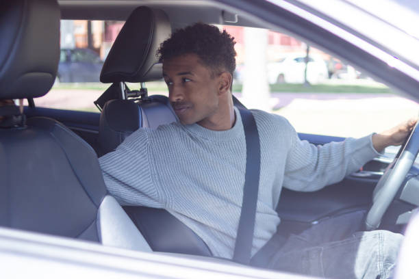 istock Young man driving a car and looking behind him 2202829809