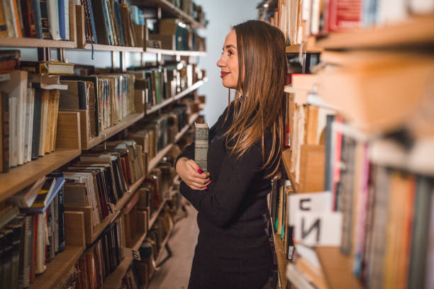 Young woman studying in a library with a librarian next to her