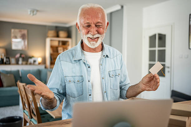 istock Senior man running small business from home, packaging and showing label 2202830322
