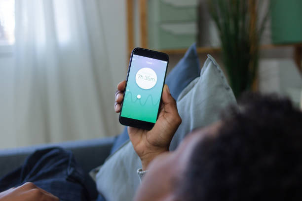 istock Young man relaxing on sofa checking sleep tracking app on smartphone 2202830608