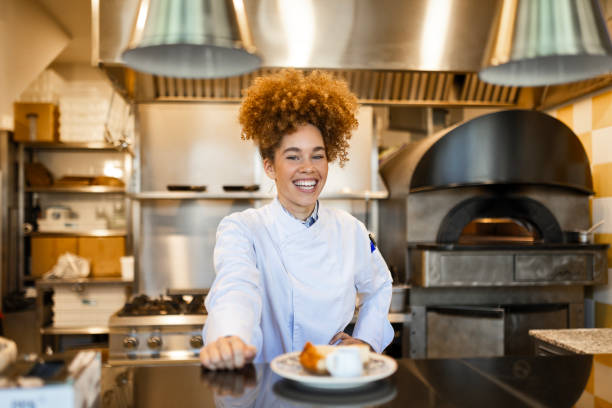 Smiling Female Chef Presenting a Dish in Restaurant Kitchen