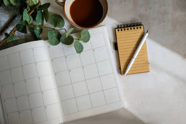 istock Planner notebook and cup of coffee on shadows background 2202832485