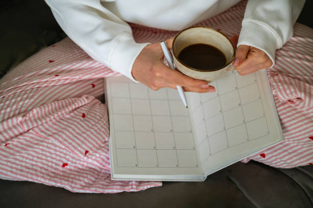 istock Unrecognizable woman with pajamas writing in her planner and drinking coffee 2202832603