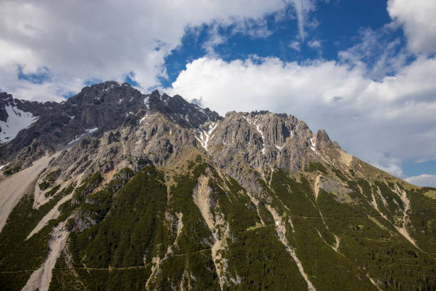 Austria Alps mountain landscape in early summer with snow, grass and rocky summits on a sunny day. Austrian mountains beautiful scenic view in Tirol near Imst