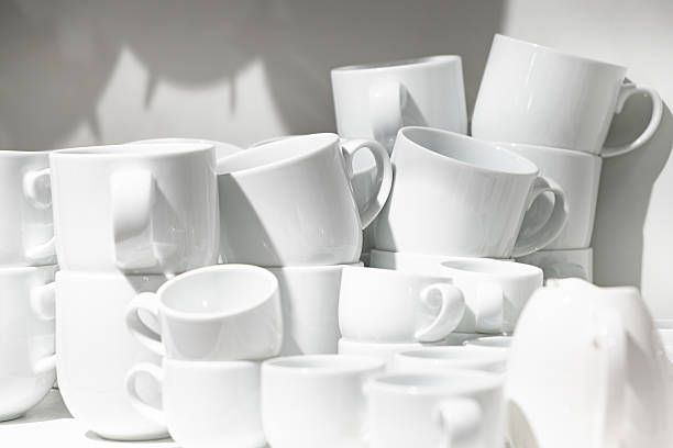 Spotted coffee cups and plates of different designs and wine glasses displayed on a shelf in a department store
