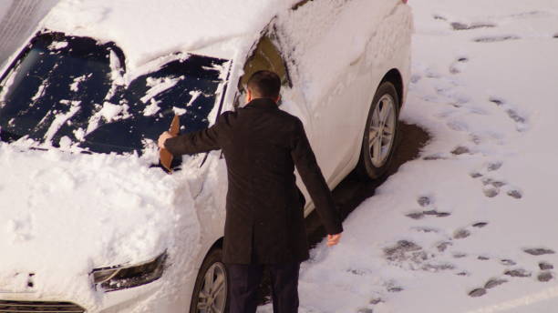 istock man cleans car from snow in the morning 2202835285