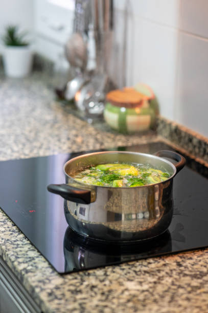 istock Cooking pot with vegetables boiling on modern induction cooker in kitchen 2202835941