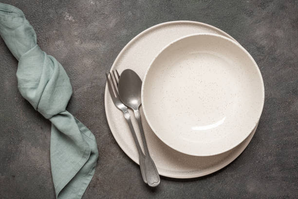 istock Two empty plates with cutlery and linen napkin on dark rustic background, top view, minimal table setting 2202836202