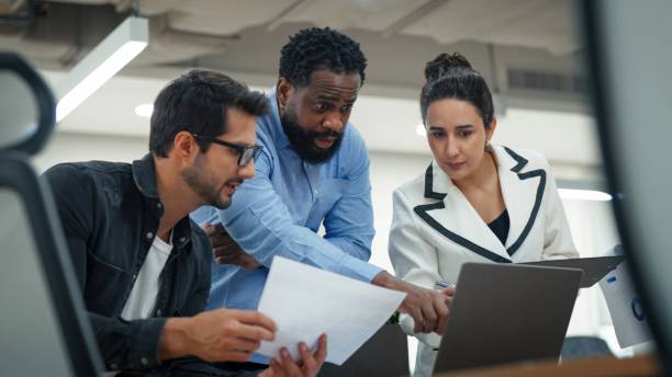 istock Multicultural group of professionals discussing market analysis in a modern office. A Black business leader presenting key strategies on a computer, fostering teamwork, creativity, and success in a corporate business meeting. 2202836285