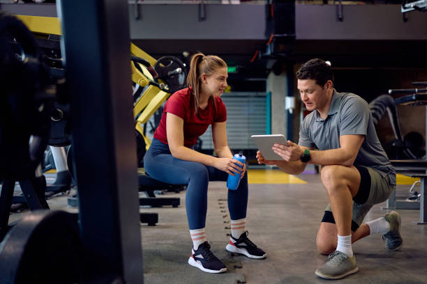 istock Young athlete and her fitness instructor analyzing plans on touchpad during sports training in a gym 2202837325