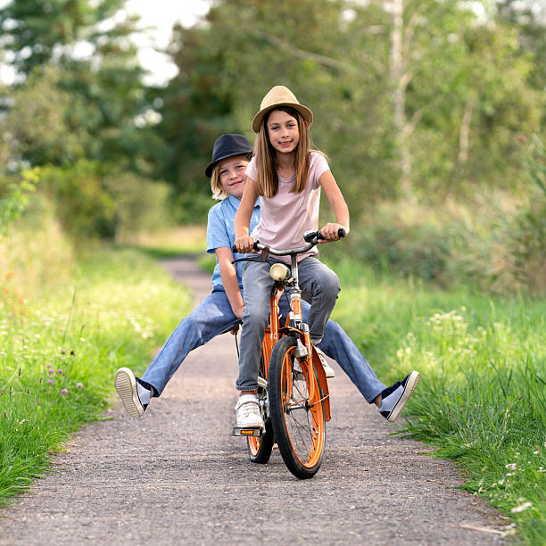 istock funny children ride together on a bicycle 2202839292