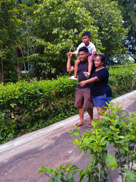 istock Father Carrying Child on Shoulders While Walking Home in Garden Path 2202841740