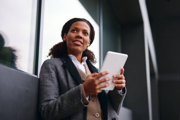 istock Smiling businesswoman using digital tablet outside office building 2202842962