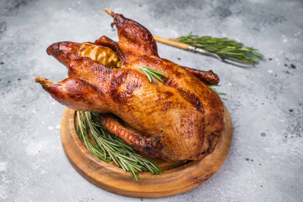 istock Baked whole duck with apples on wooden board. grey background. top view 2202843273