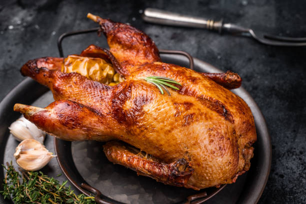 istock Roasted whole goose on steel tray. black background. top view 2202843282