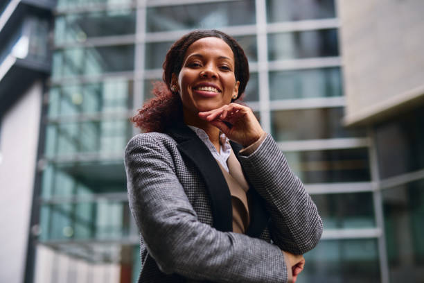 istock Confident businesswoman smiling outside a modern office building 2202843339
