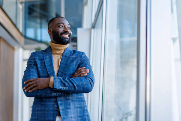 Confident businessman smiling with arms crossed in modern office