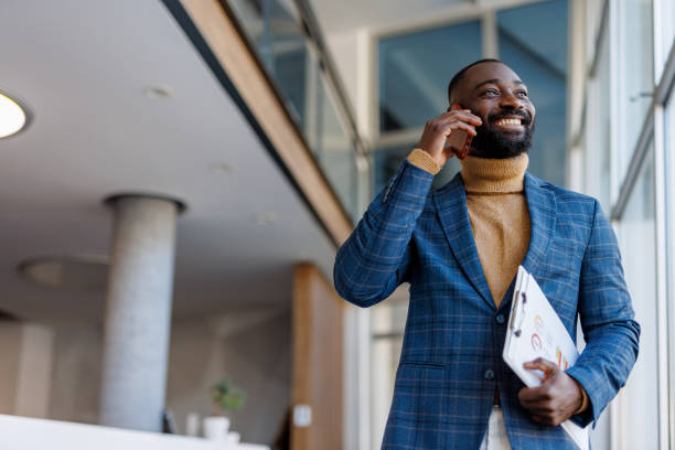 istock Smiling businessman talking on phone in modern office holding clipboard 2202844821