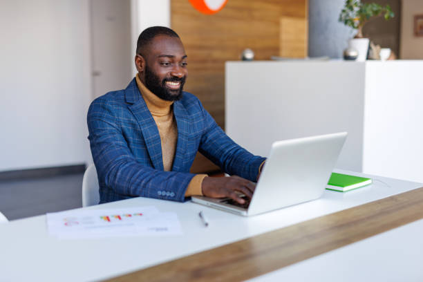 istock Smiling businessman working on laptop in modern office 2202844866