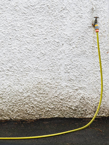 istock Yellow rubber hose and wall mounted holder outdoors 2202852273