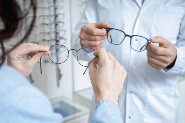 istock Optic shop assistant showing eyeglasses to a client in a optic shop 2202853997