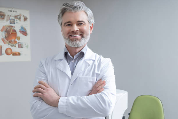 istock Gray-haired bearded mid aged caucasian doctor looking confident and contented 2202854061
