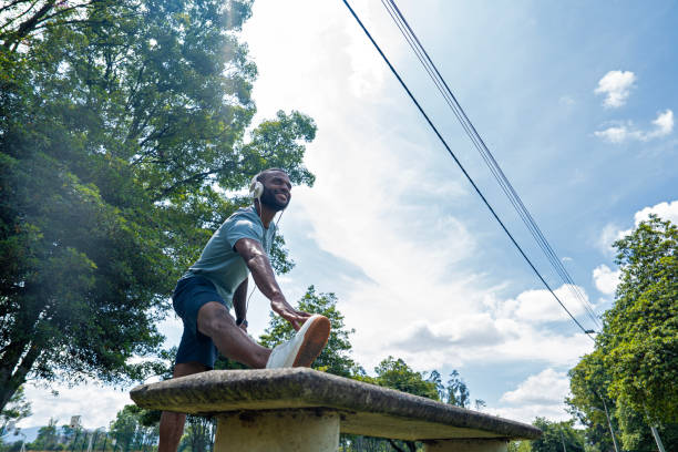 An African American man performs leg stretches in the park, waking up his muscles and preparing his body for an outdoor workout.