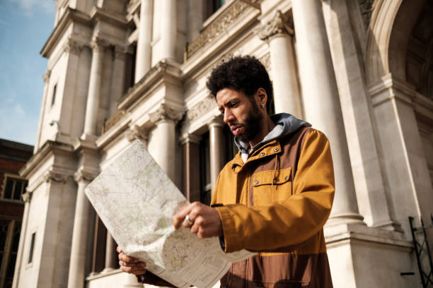 Young man reading a map in front of a historical building, exploring a new city during his vacation, enjoying the architecture and culture of the place