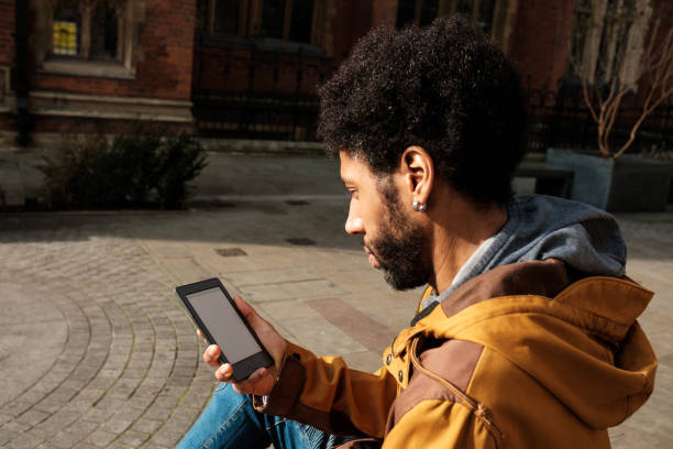 istock Young man reading an ebook outside on a sunny day 2202861183